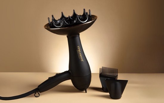Zwarte Curlsmith haardroger met diffuser en opzetstukken op een beige achtergrond.