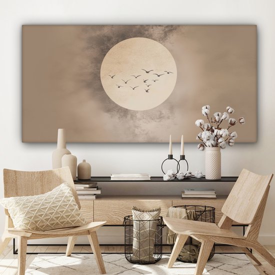 Canvas met beige tinten, zachte cirkel en vogels, boven een houten meubel met twee houten stoelen.