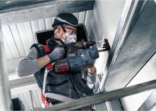 Vakman met helm en masker gebruikt een blauwe Bosch boorhamer met ProCORE 18V accu op een bouwplaats.