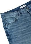 Detail van de tailleband en zakken van een lichtblauwe jeans.