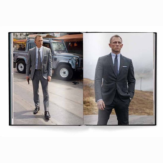 Daniel Craig in een grijs pak met blauwe das en een lichte grijze Land Rover.