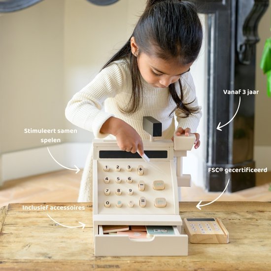Meisje in wit gebreid vest speelt met houten speelgoedkassa en pinapparaat. Stickers geven aan 'vanaf 3 jaar', 'stimuleert samenspelen' en 'FSC gecertificeerd'.