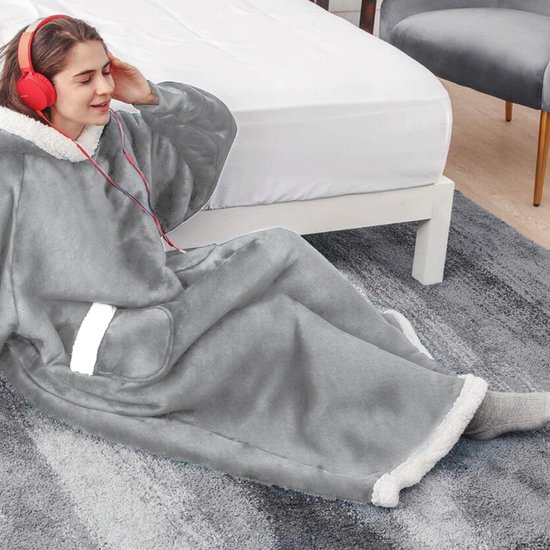 Vrouw met koptelefoon zit op de grond in een zachte, grijze hoodie deken met witte fleece capuchon en zakken.