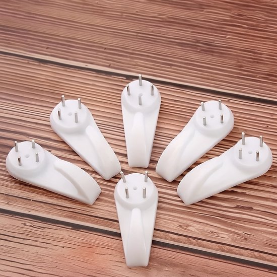 Zes witte ophanghaken met metalen spijkers, gerangschikt op een houten ondergrond.