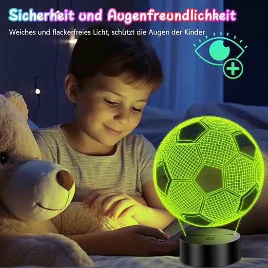 Jongetje dat 's nachts naar een groen oplichtende 3D-voetballamp kijkt, naast een teddybeer.