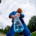 Blauwe Kambukka drinkfles gedragen door een persoon met een blauwe outfit, gefotografeerd van onderaf.