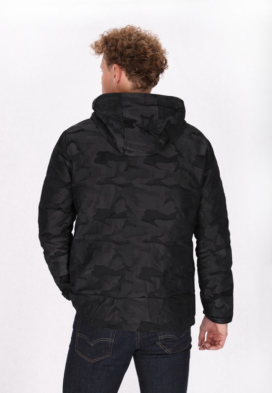 Model van achteren gezien in een zwarte camouflageprint jas met capuchon en spijkerbroek.