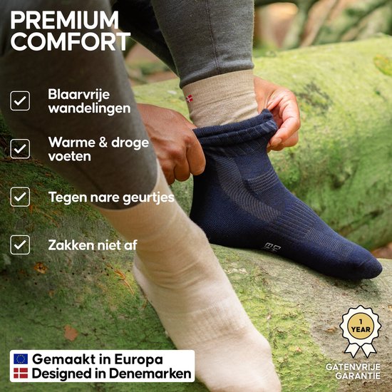 Close-up van een persoon die donkerblauwe wandelsokken aantrekt, met de tekst 'Premium comfort', 'Gemaakt in Europa' en een garantie-icoon