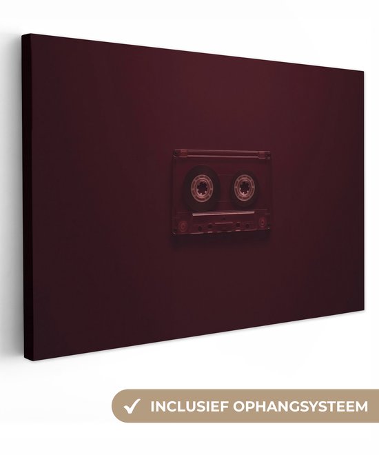 Een bordeauxrode cassetteband op een effen donkerrode achtergrond, met de tekst 'Inclusief ophangsysteem'.