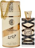 Oud Mood parfumfles met gouden dop, omwikkeld met zwart lint met "Oud Mood" erop. Naast een cilinderverpakking met gouden opdruk.