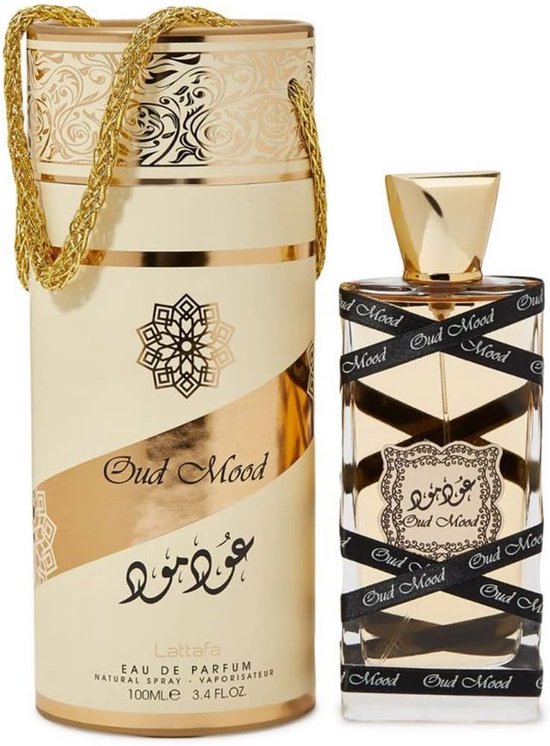 Oud Mood parfumfles met gouden dop, omwikkeld met zwart lint met "Oud Mood" erop. Naast een cilinderverpakking met gouden opdruk.