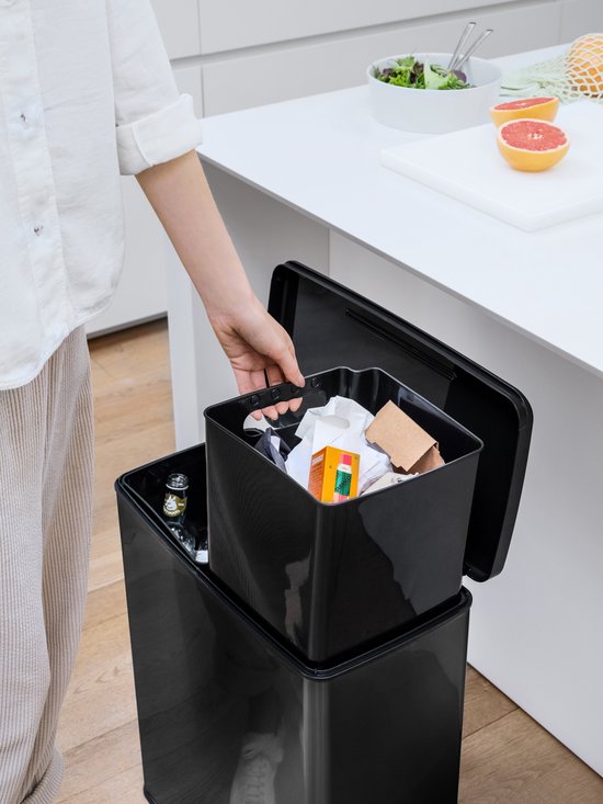 Een hand pakt een zwarte binnenemmer uit de Curver Deco Bin.