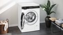 Wasmachine Siemens iQ500 met geopende deur, naast een mand met wasgoed.