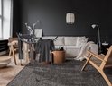 Antraciet droogrek met kleding in een modern interieur met bank en fauteuil.