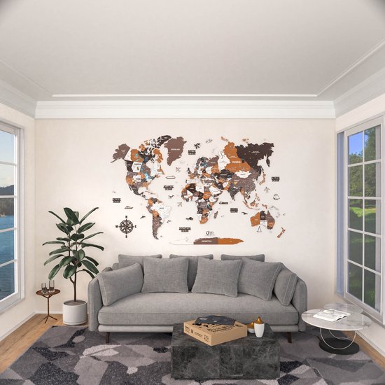 Een grote, bruine en witte houten wereldkaart hangt boven een grijze bank in een woonkamer.