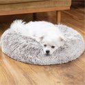 Kleine witte hond op een ronde, zachte, grijze mand.