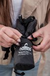 Vrouw met handen die de zwarte Nomad Mahon Ultralite 18L rugzak oprollen.