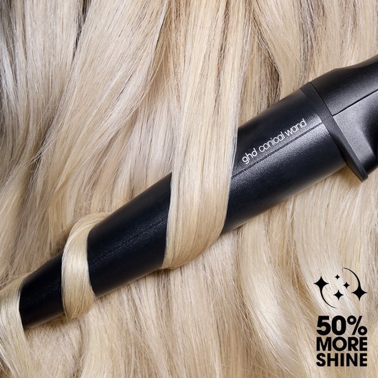 Een blonde lok wordt om een zwarte ghd conische krultang gewikkeld. Tekst '50% more shine'.