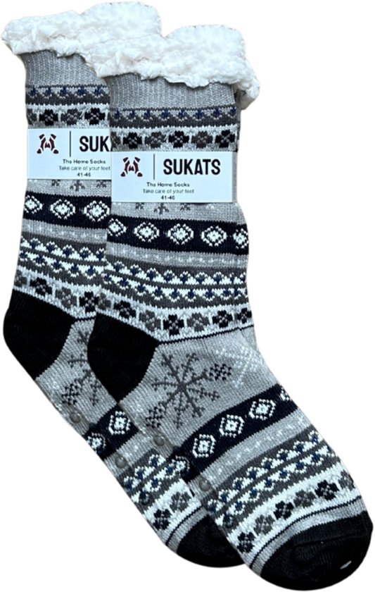 Sukats huissokken in grijs met zwart, wit en grijze patronen, inclusief sneeuwvlok. Witte, fluffy rand. Zwarte anti-slip noppen aan de zool.