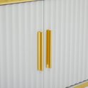 Detail van de verticale ribbels en gouden handgrepen op de witte kastdeuren.