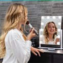 Vrouw met blonde haren gebruikt make-up met een Mirlux Hollywood spiegel met verlichting.