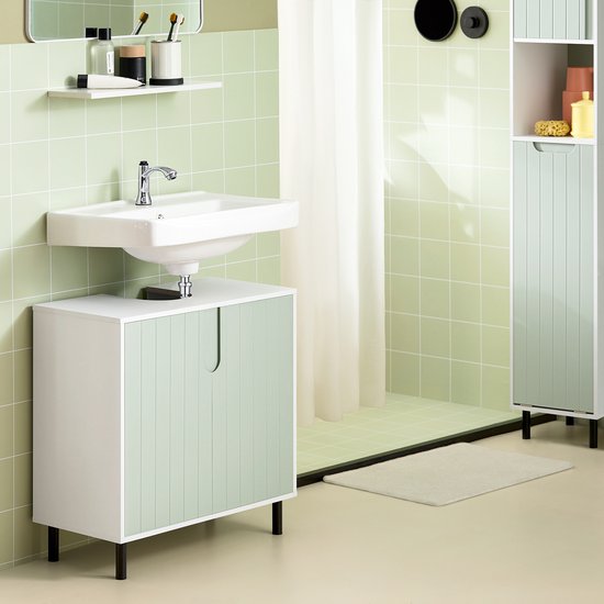 Badkamer met een witte onderbouwkast met groene, gegroefde deuren, een witte wasbak en een spiegel. Naast een hoge witte kast.