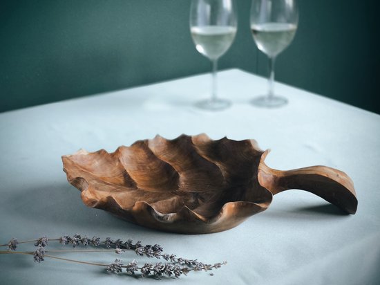 Houten fruitschaal met gegolfde rand en handvat, met lavendeltakjes op tafel.