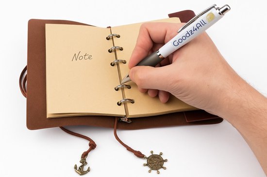 Hand schrijft "Note" in een bruin lederen notitieboek met blanco papier, met een "Goodz4All" pen.