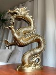 Gouden draak ornament op een tafel, met zachte meubels op de achtergrond.