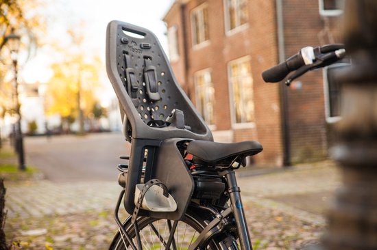 Zwarte fietsstoel voor kinderen, gemonteerd op een bagagedrager van een e-bike.