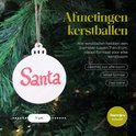 Houten kerstbal met de tekst 'Santa' in rode letters, hangend aan een kerstboom.