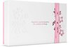 Witte cadeauverpakking van Rituals met reliëfdecoraties van bloesemtakken en de tekst 'Happiness can be found in the smallest of things'. De verpakking is omwikkeld met roze linten.