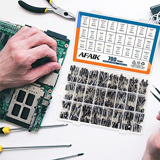 Grijze koffer met 700 stuks elektrolytische condensatoren, naast een printplaat en gereedschap.