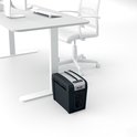 Zwarte Rexel papierversnipperaar naast een bureau op kantoor.