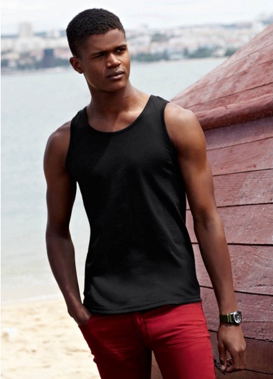 Le mannequin porte un débardeur noir et un pantalon rouge sur une plage.