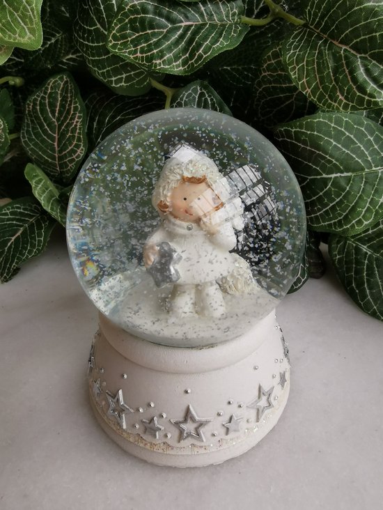 Sneeuwbol  wintermeisje gekleed in wit met puntmuts en zilveren hart, sterretje  of stokje in de handjes op witte sokkel met zilveren sterren