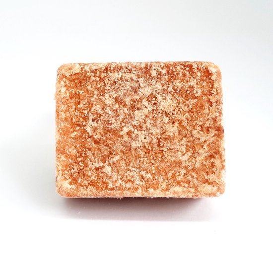 Een amberblokje met een korrelige, bruine textuur op een witte achtergrond.