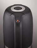 Close-up van de zwarte Tefal waterkoker met een verlichte aan/uit-knop en een zilveren ring.