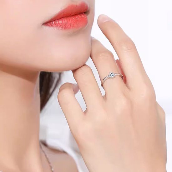 Sluiting van de ring met hartvormige steen om de vinger van een vrouw.