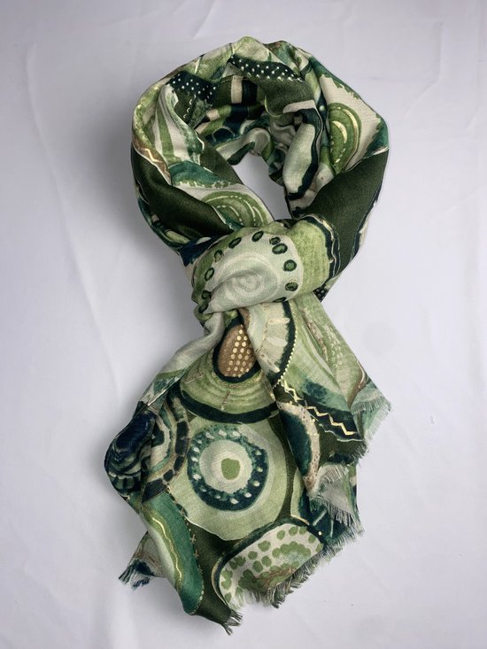 Groene sjaal met cirkelpatroon en gouden accenten, gedrapeerd in een knoop.