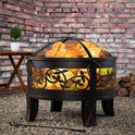 Gardebruk vuurkorf met decoratief bladmotief in een tuin met bakstenen muur en houten tafel.