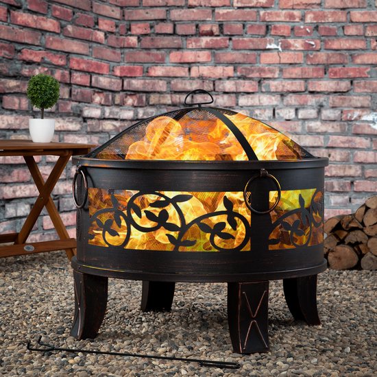 Gardebruk vuurkorf met decoratief bladmotief in een tuin met bakstenen muur en houten tafel.