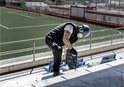 Man met veiligheidsuitrusting gebruikt een boorhamer op een trap.
