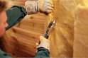 Man met werkhandschoenen bevestigt isolatiemateriaal met een zilveren hamertacker.