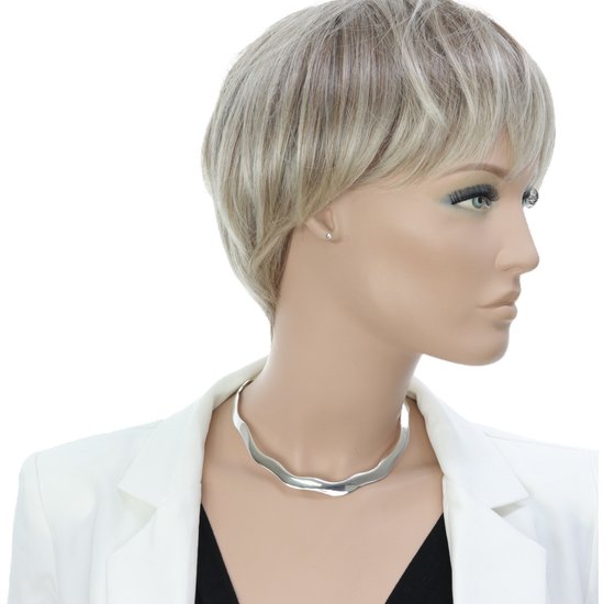 Model draagt een zilveren spang met golvende, asymmetrische vorm over een witte blazer.