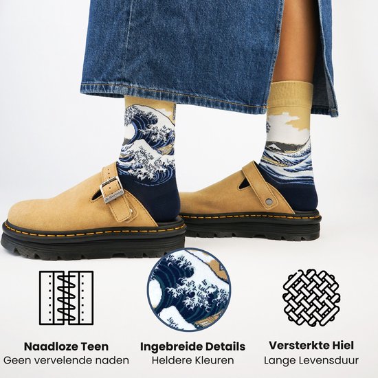 Een persoon draagt donkerblauwe sokken met een print van 'De Grote Golf van Kanagawa' en beige instappers.