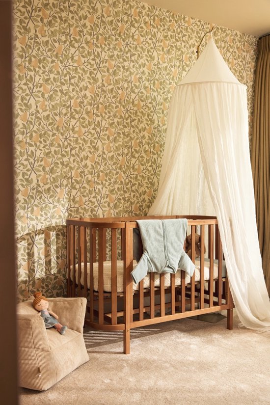 Lichtgroene baby slaapzak over een ledikant in een kinderkamer met perenbehang.