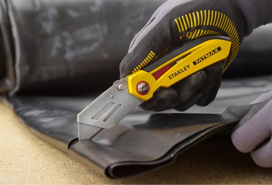 Grijze werkhandschoenen snijden in zwart materiaal met een gele Stanley FatMax vouwmets.