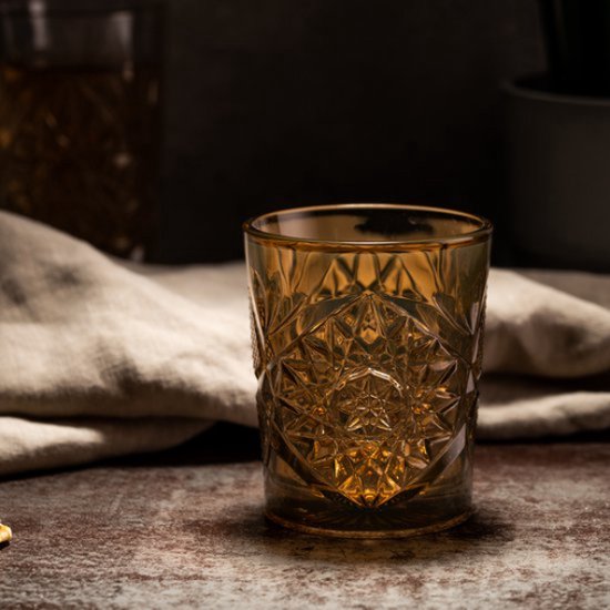 Amberkleurig glas met geometrisch patroon op rustieke ondergrond.