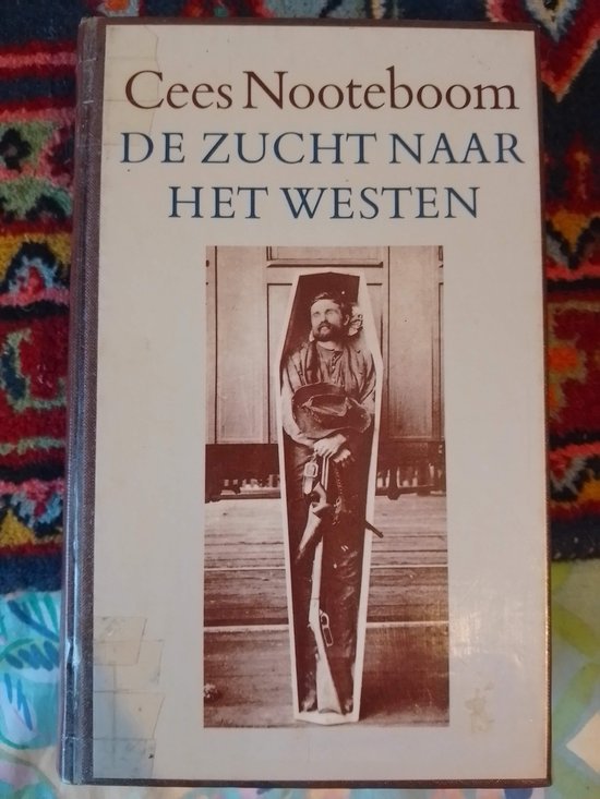 Boek met de titel 'De Zucht naar het Westen' van Cees Nooteboom. Op de voorkant een foto van een man in een kist.